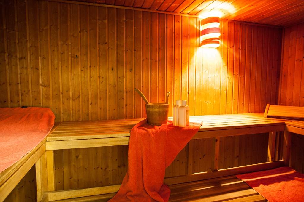 Holzsauna mit Bänken, Handtuch und Saunakübel.